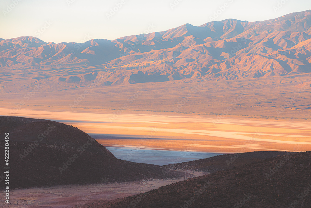 Dramatic golden light and shadow on the rugged terrain of the badlands landscape at Badwater Basin in Death Valley Park National Park, California, USA.