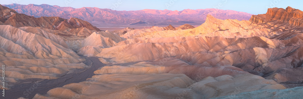 Panorama sunset or sunrise view of Zabriskie Point and the rugged sedimentary rock terrain of the badlands landscape in Death Valley Park National Park, USA.