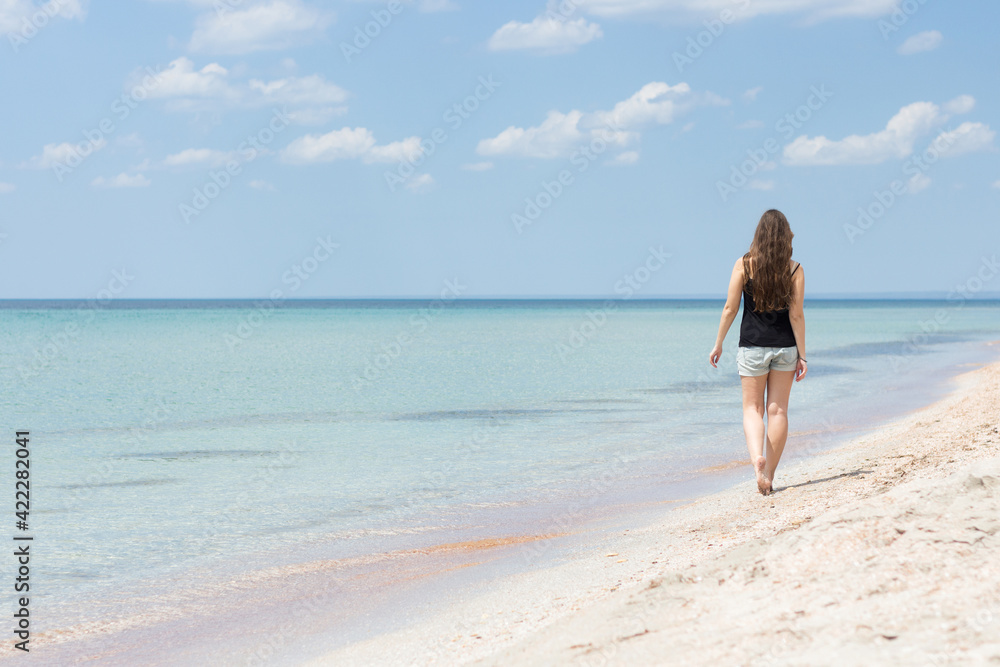 Young woman walking along the sea beach