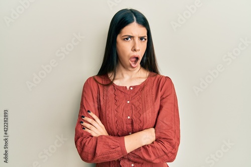 Young hispanic woman wearing casual clothes in shock face, looking skeptical and sarcastic, surprised with open mouth © Krakenimages.com