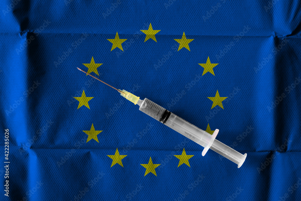 Concept of the ongoing efforts by the European Union to deliver and distribute COVID-19 Vaccine with a syringe ready to use on a European Flag.