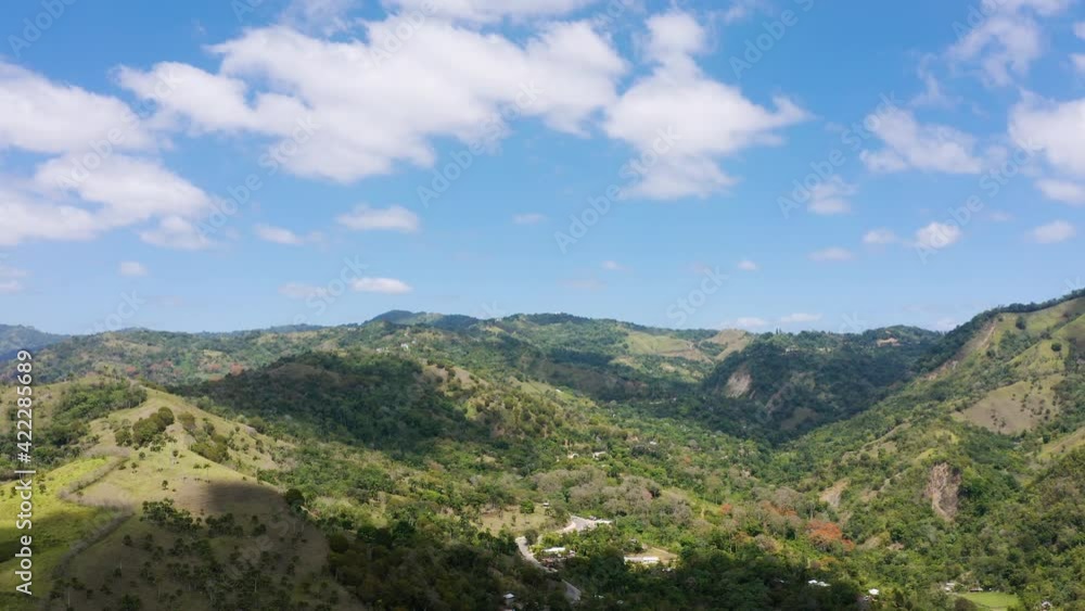 Tropical highlands densely covered with palm thickets. A beautiful mountain landscape, brightly lit by the summer sun. A beautiful landscape with thick snow-white clouds floating across the blue sky. Tropical highlands densely covered with palm thickets. A beautiful mountain landscape, brightly lit by the summer sun. A beautiful landscape with thick snow-white clouds floating across the blue sky.