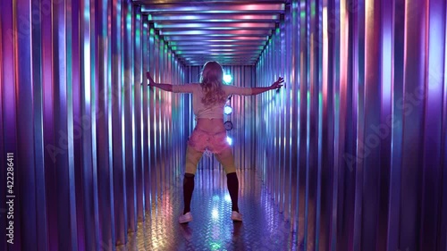 blonde sexy lady is twerking in illuminated corridor, rear view of sexy female body photo