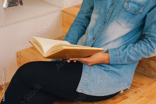 Happy woman reading a book and relaxing comfortably. Female hands with book 