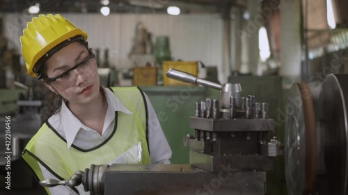 Asian professional mechanical engineer or operation woman wear uniform goggles safety working on workshop metal lathe industrial manufacturing factory, Heavy industry lathe worker woman, slow motion