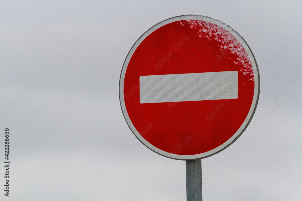 Stop road sign. Bright red circle, white rectangle. Gray blurred sky on background. Stop road sign. Bright red circle, white rectangle. Gray blurred sky on background.