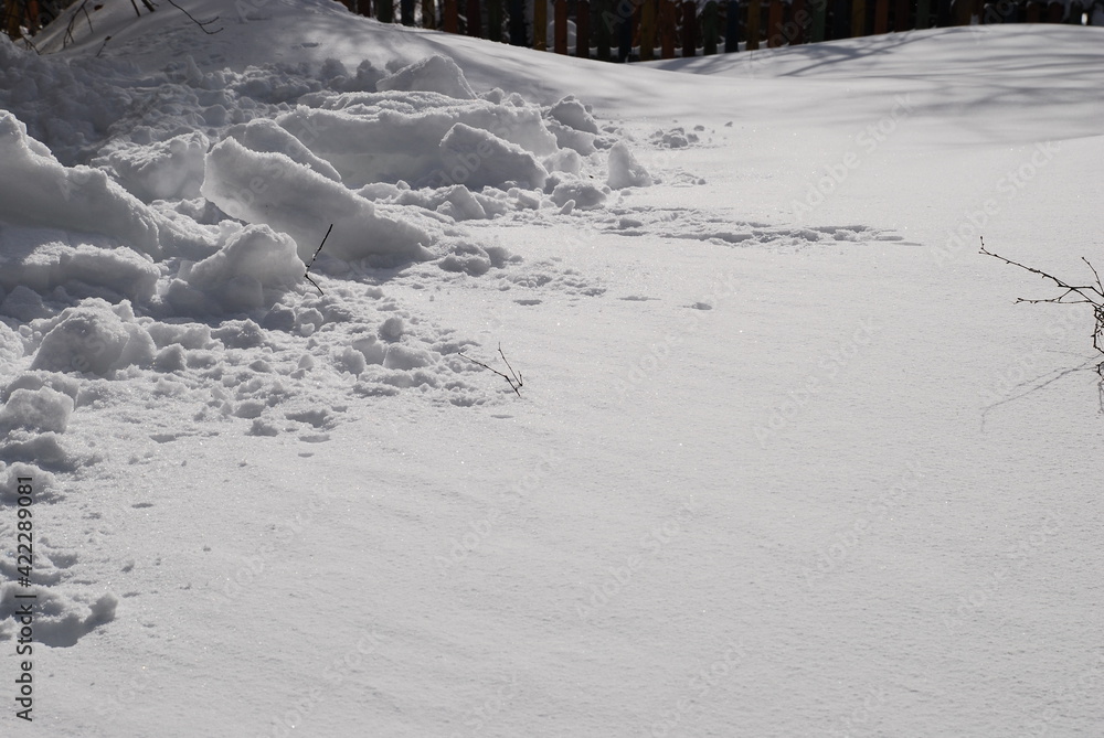 Smooth snow surface under the sun's rays. The texture of the snow cover that covered the ground. Part of the snow is dug up and lies in an uneven hill. Smooth snow surface under the sun's rays. The texture of the snow cover that covered the ground. Part of the snow is dug up and lies in an uneven hill.