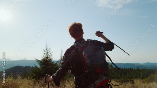Man raising hands in air during hike in mountains. Happy hiker feeling freedom