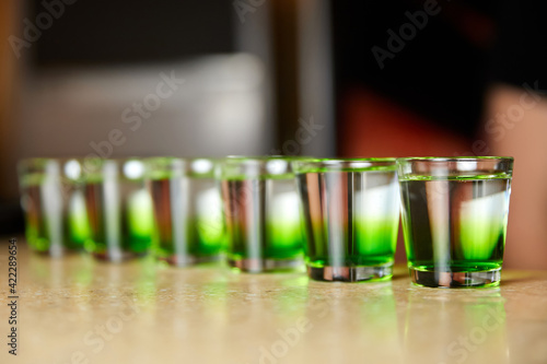 Several white-green alcoholic drinks shots on the bar counter. Close-up, selective focus © marketlan