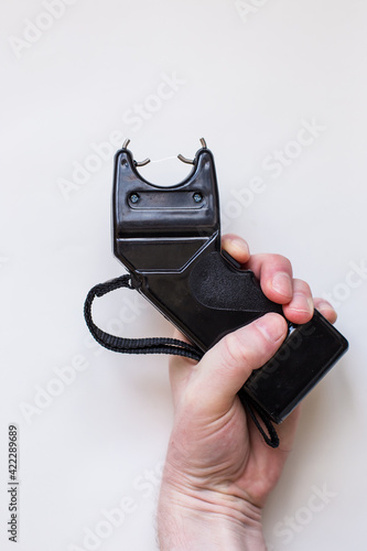 Black stun gun in the hand of a man on a white background photo