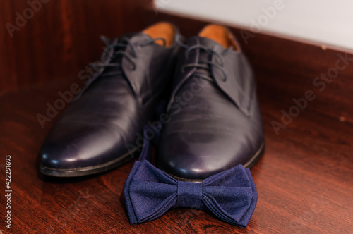 Blue bow tie on blue classic shoes on brown background © Galka3250