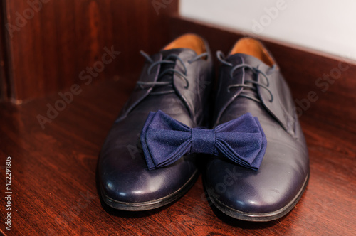 Blue bow tie on blue classic shoes on brown background