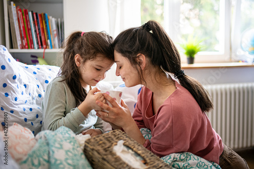 Obraz na plátně Mother looking after sick small daughter in bed at home.