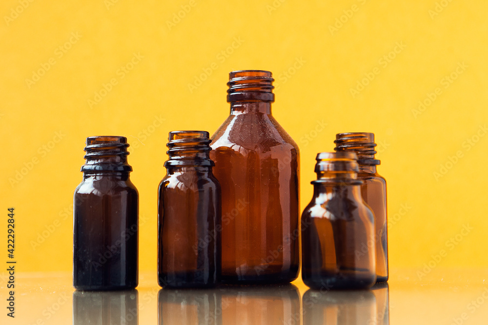 Dark brown phials on yellow background. Small empty bottles