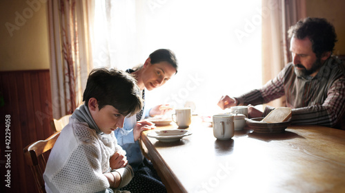 Tableau sur toile Angry small girl with parents sulking indoors at the table at home, poverty concept