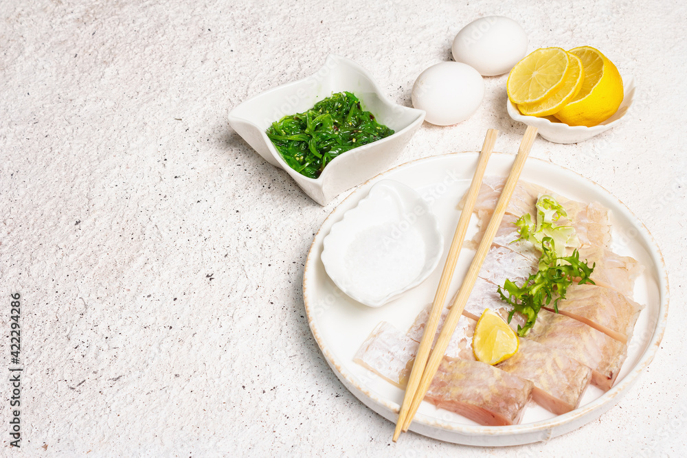 Pieces of raw hake, chukka salad, lemon wedge, fresh herbs, eggs as food preparation concept Pieces of raw hake, chukka salad, lemon wedge, fresh herbs, eggs as food preparation concept