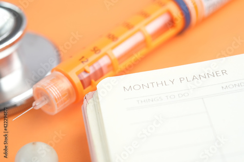 Insulin pen and weekly planner on table  photo