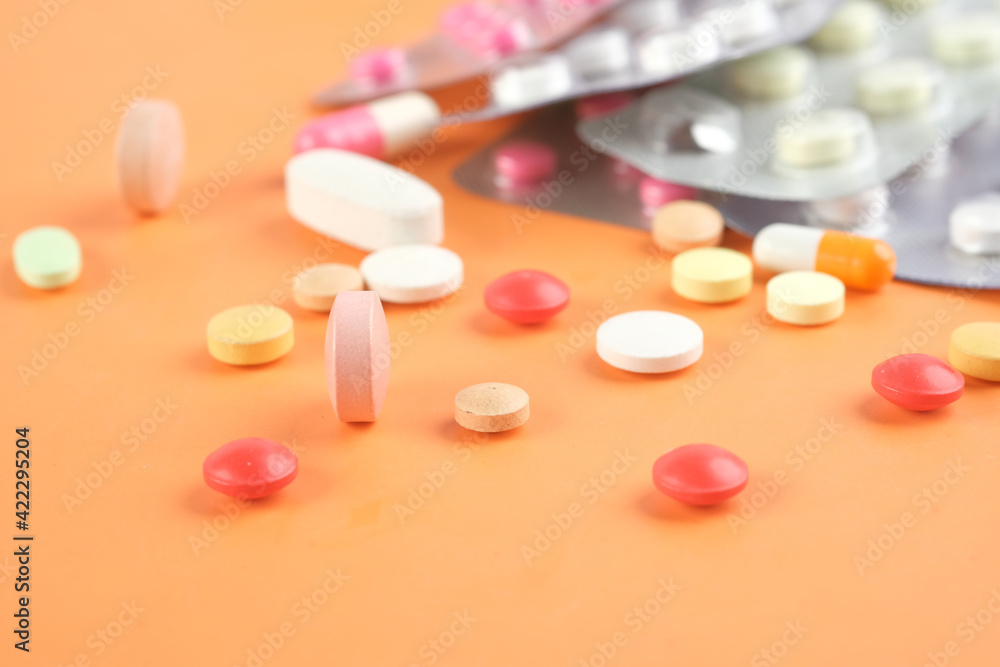 Close up of many colorful pills and capsules on orange background Close up of many colorful pills and capsules on orange background