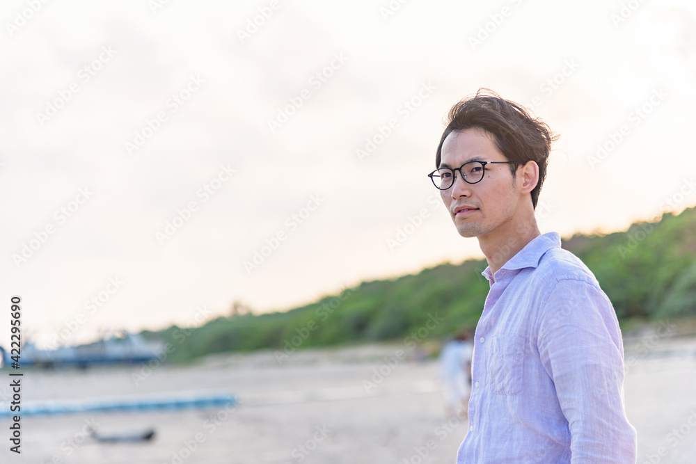 夕暮れのビーチで佇む男性 夕暮れのビーチで佇む男性
