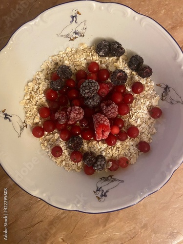 Oatmeal porridge, flakes with raspberries, blackberries and currant paint. Proper, healthy nutrition.