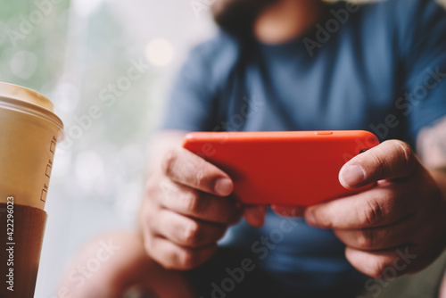 Man with takeaway coffee using smartphone