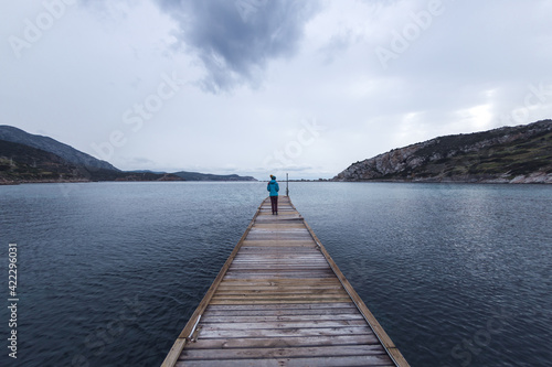 A girl stands on the pier and looks at the sea