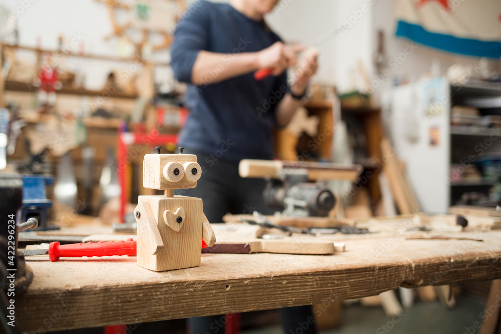 children's wooden toy robot stands on workbench surrounded by carpentry tools