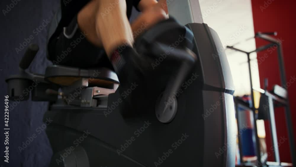 Man in the gym, young man trains on a elliptical bike simulator, aerobic exercise and endurance training Man in the gym, young man trains on a elliptical bike simulator, aerobic exercise and endurance training
