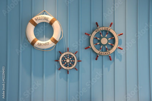  White life buoy on blue wooden wall, rudder boat helm with welcome message