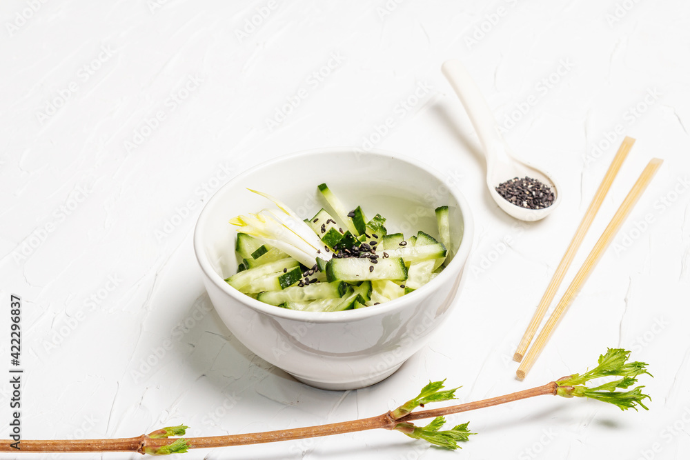 Fresh cucumber salad with sesame seeds in a white ceramic bowl Fresh cucumber salad with sesame seeds in a white ceramic bowl