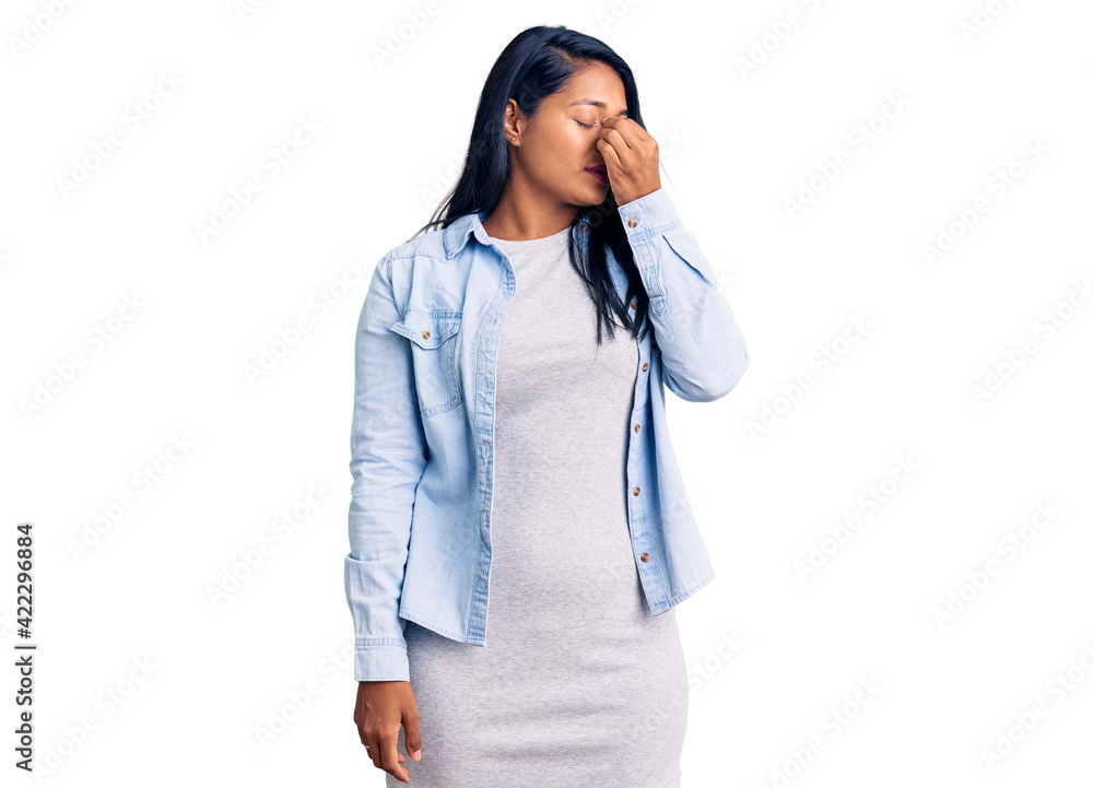 Hispanic woman with long hair wearing casual denim jacket tired rubbing nose and eyes feeling fatigue and headache. stress and frustration concept. Hispanic woman with long hair wearing casual denim jacket tired rubbing nose and eyes feeling fatigue and headache. stress and frustration concept.