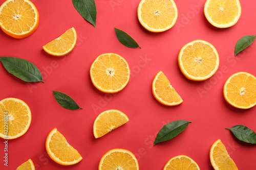 Slices of delicious oranges on red background, flat lay
