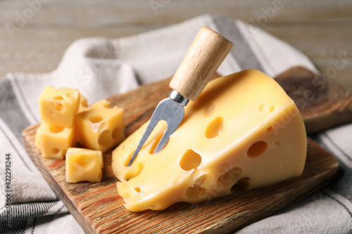 Tasty fresh cheese with fork on wooden board, closeup photo