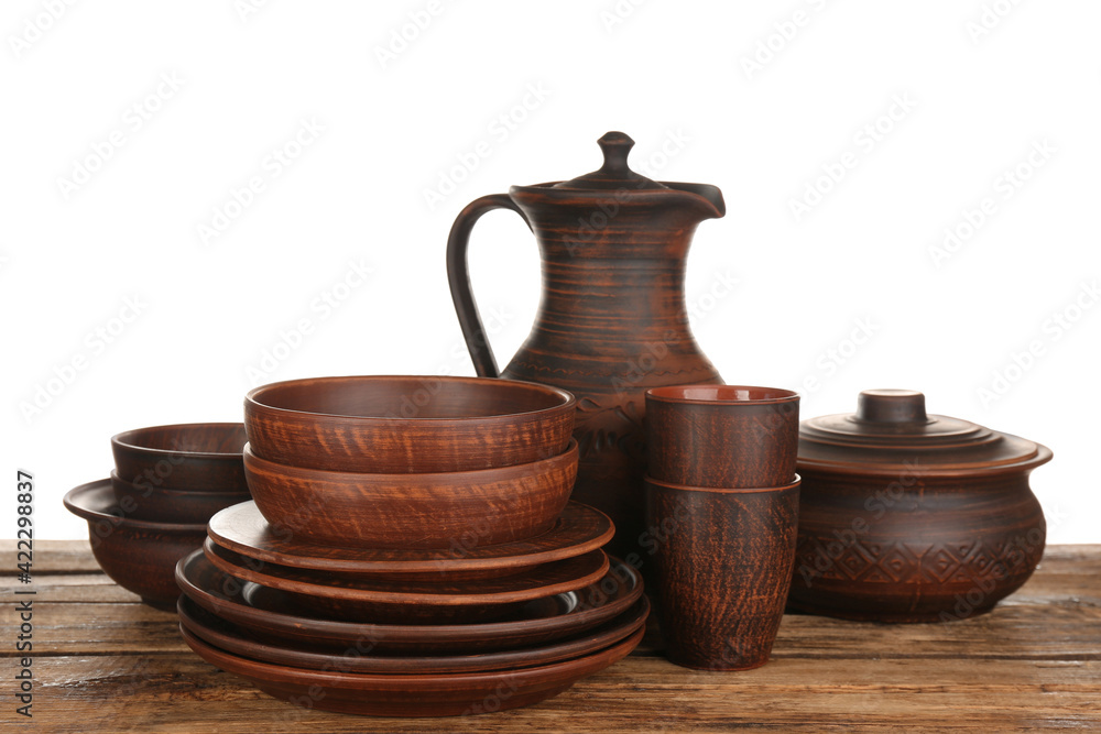 Different clay dishware on wooden table against white background