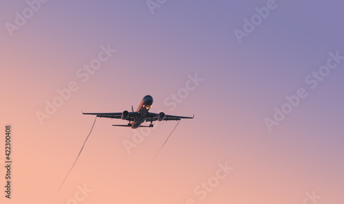 A plane in the sky at sunset. Background, wallpaper with an airplane. Negative space on one sides (leftward) of the photo. 