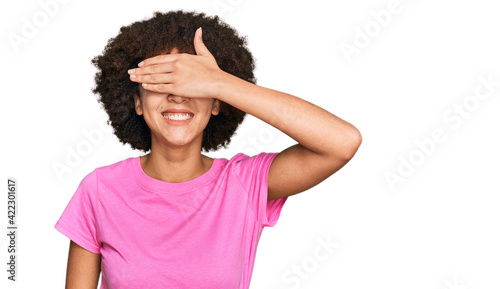 Young hispanic girl wearing casual clothes smiling and laughing with hand on face covering eyes for surprise. blind concept.