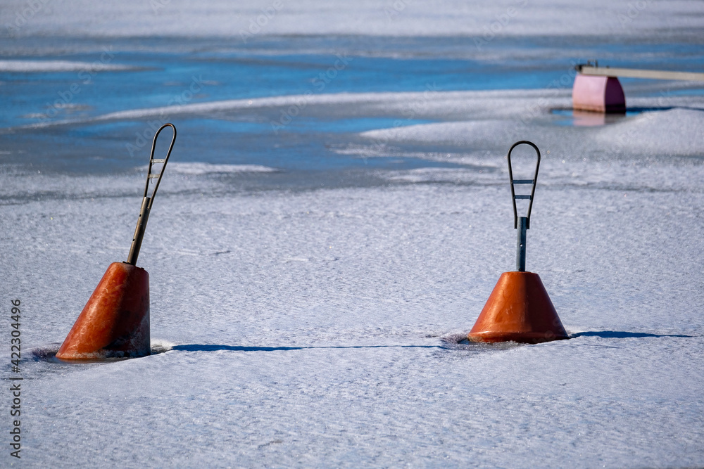 A closeup of two mooring buoys floating in the middle of frozen sea on a sunny spring day. A closeup of two mooring buoys floating in the middle of frozen sea on a sunny spring day.