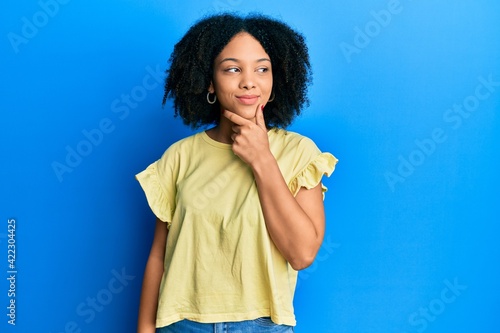 Young african american girl wearing casual clothes with hand on chin thinking about question, pensive expression. smiling with thoughtful face. doubt concept.