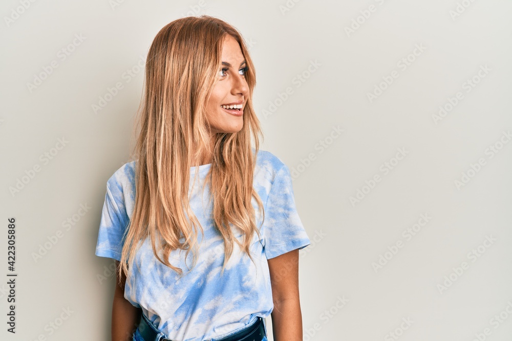 Beautiful blonde young woman wearing tye die tshirt looking to side, relax profile pose with natural face and confident smile. Beautiful blonde young woman wearing tye die tshirt looking to side, relax profile pose with natural face and confident smile.