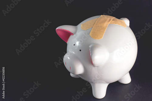 Piggy bank with adhesive medical plasters on it  black background