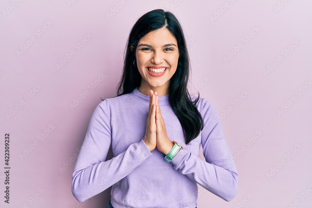 Young hispanic woman wearing casual clothes praying with hands together asking for forgiveness smiling confident. Young hispanic woman wearing casual clothes praying with hands together asking for forgiveness smiling confident.