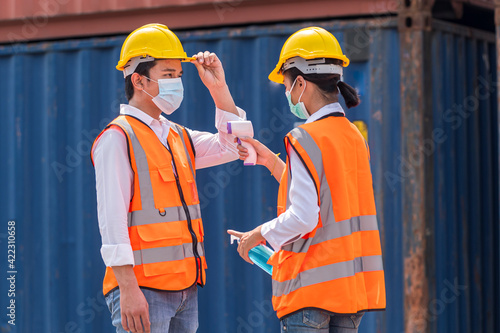 Factory workers wear face mask and safety dress cleaning hand with alcohol sanitizer gel and stand on queue at outdoor warehouse - safety and health protect coronavirus protocol concept