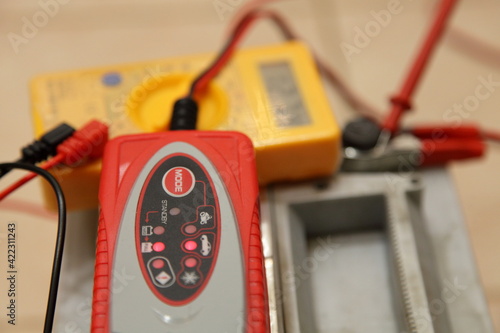 Valokuva Smart automatic charger unit on blurred digital multimeter voltmeter and full ch