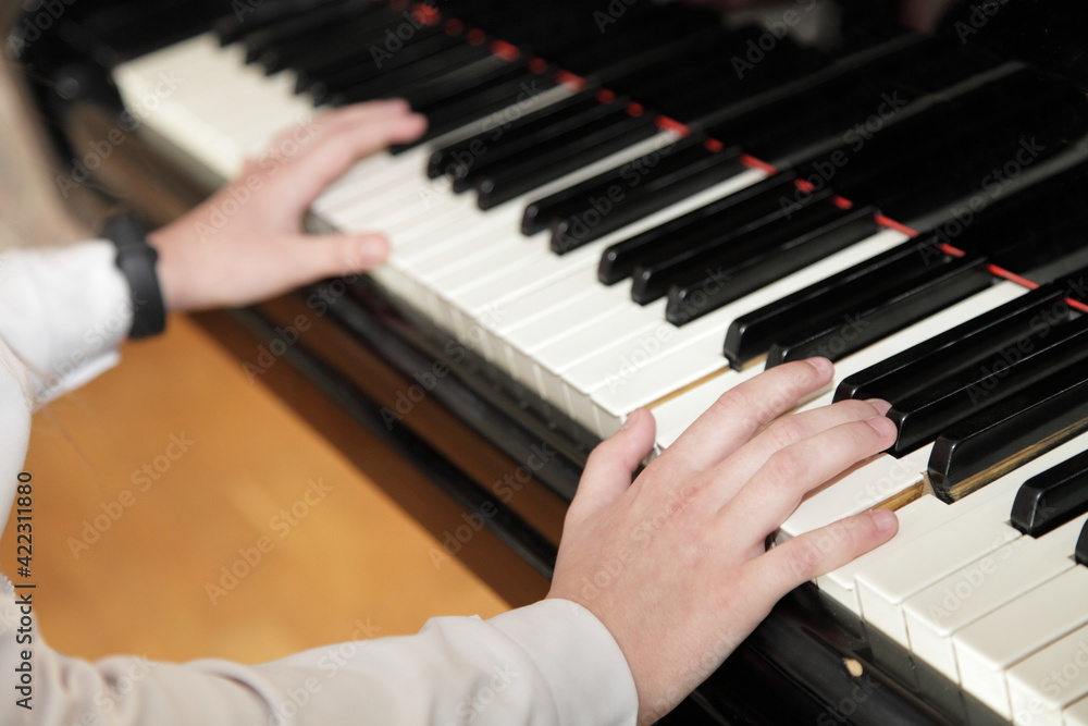 Fototapeta premium White hands of a piano girl playing the Grand piano closeup top side view, classic music school education