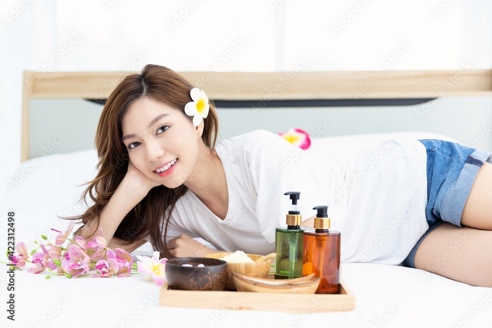 Young Asian women are enjoying the preparation of spa equipment. Smiling young girl waiting for a DIY home spa treatment in her white bedroom. Young Asian women are enjoying the preparation of spa equipment. Smiling young girl waiting for a DIY home spa treatment in her white bedroom.