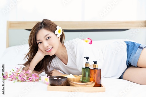 Young Asian women are enjoying the preparation of spa equipment. Smiling young girl waiting for a DIY home spa treatment in her white bedroom.