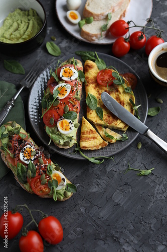 Delicious and healthy breakfast. Toast with fish, avocado and quail eggs on a plate with omelet. Proper nutrition.