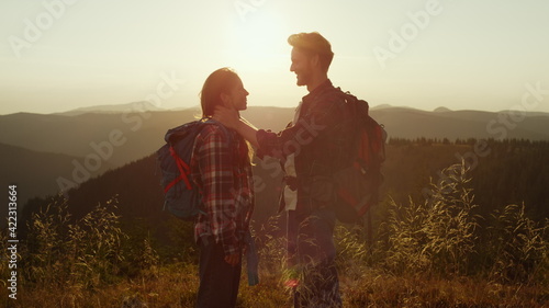 Loving girl and guy spending time together in mountains at sunset