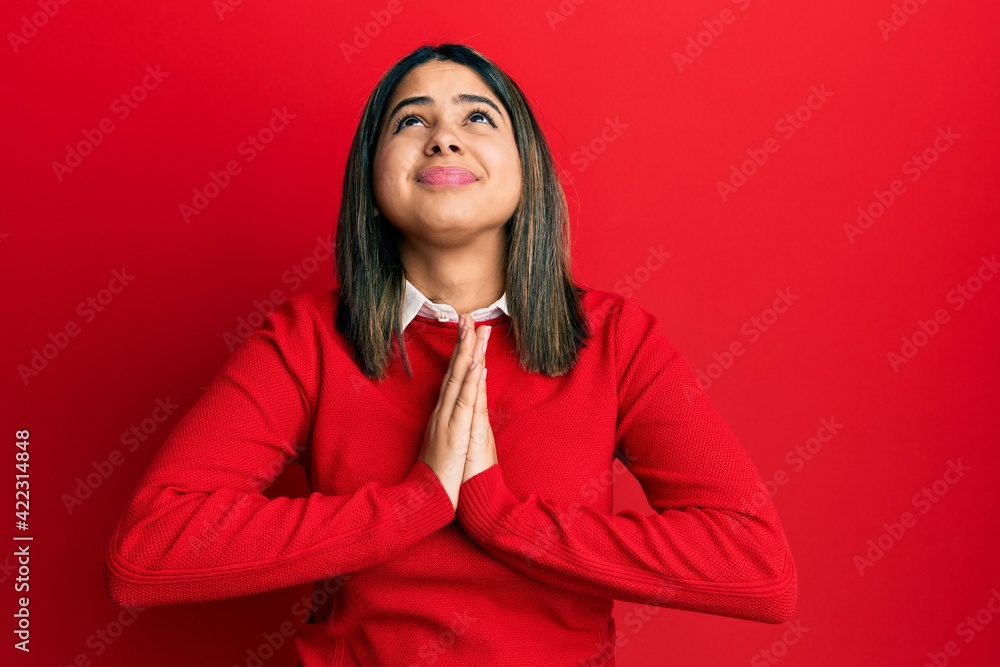 Young latin woman wearing casual clothes begging and praying with hands together with hope expression on face very emotional and worried. begging. Young latin woman wearing casual clothes begging and praying with hands together with hope expression on face very emotional and worried. begging.