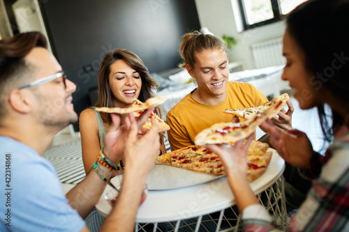 Spending time with friends. Group of cheerful young people talking and eating pizza together